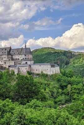 Vianden white concrete castle surrounded by green trees under white clouds and blue sky during daytime