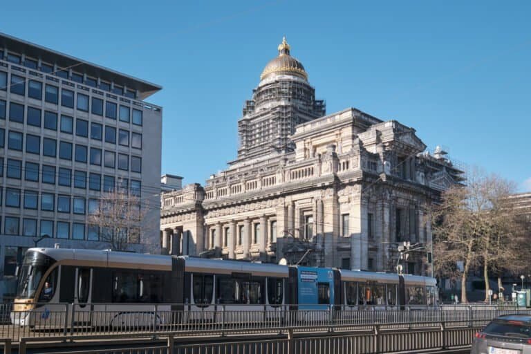 A tram on the tracks in front of palace of justice, a large abandoned court building in brussels, belgium