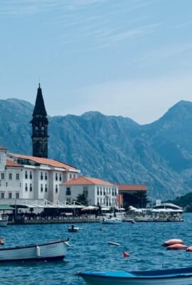 Explore the charming town of perast, montenegro, by the water with a stunning mountain backdrop.