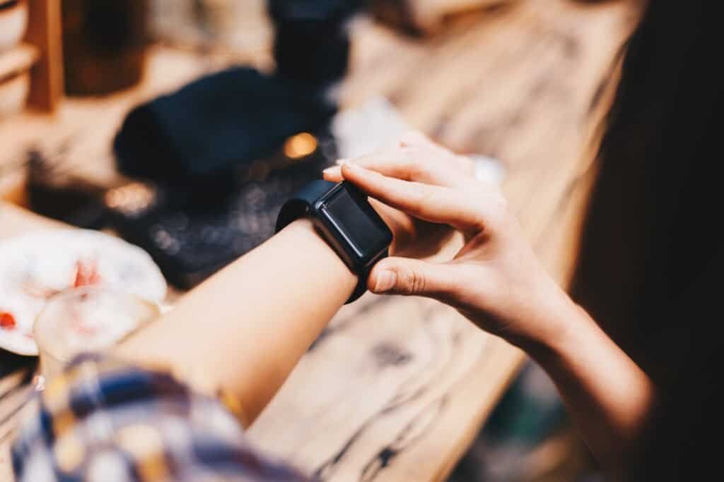 Women hand wear smart watch sitting in cafe with phone