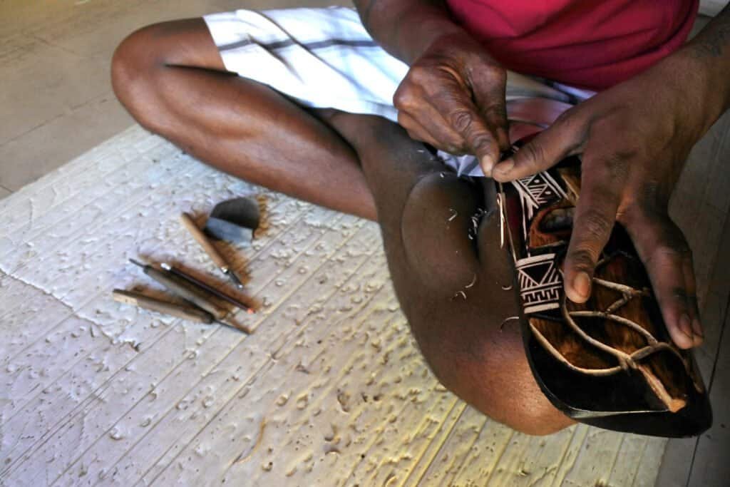 Hands of indigenous fijian man wood carving a sea turtle.