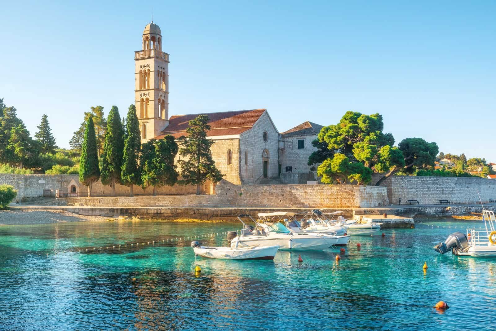 Turquoise water of adriatic sea bay on hvar island with franciscian monastery and boats in dalmatia region, croatia at sunrise. Summer vacation destination